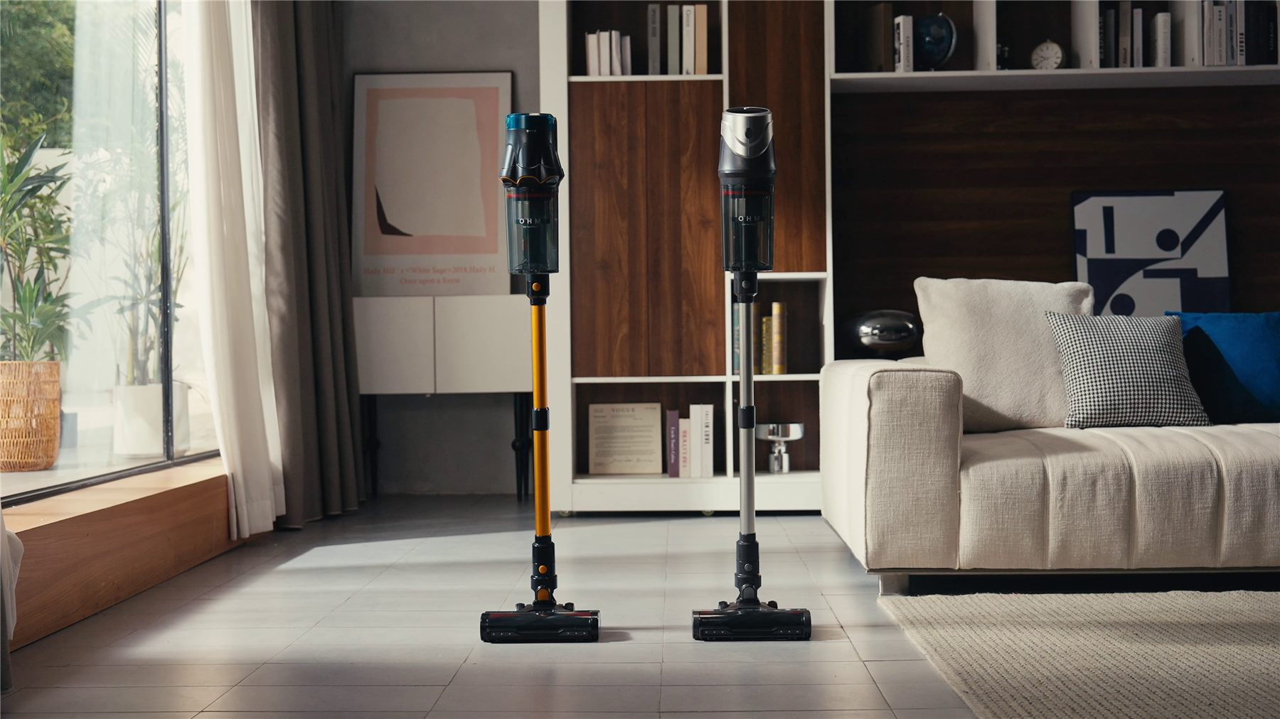 OHM Cosmo and Lunar cordless vacuums standing side by side in a sunlit living room